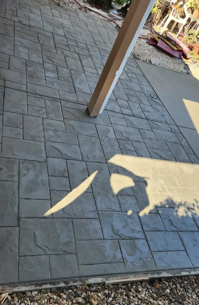 Stamped concrete walkway with a stone pattern beside a wooden post