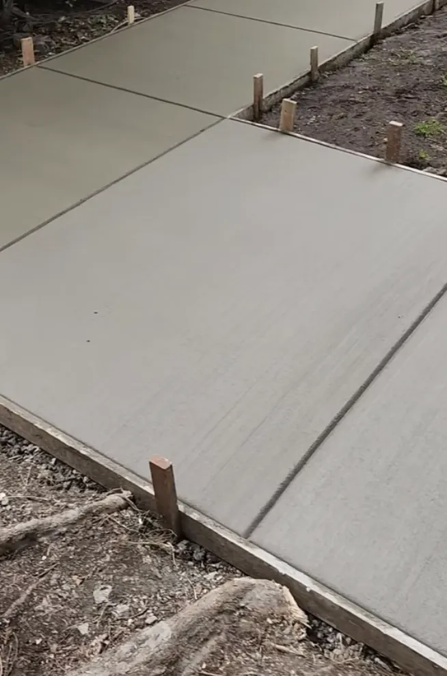Newly poured gray concrete slab with formwork and control joints