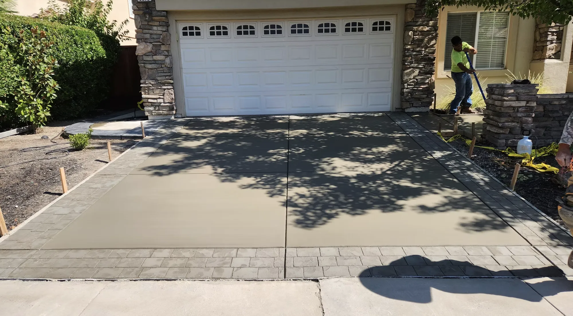 New concrete driveway in front of a two car garage with a stamped border